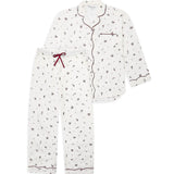 A two-piece pajama set featuring a long-sleeve button-front top and matching pants in white with a small dark floral print, accented by dark red piping and a red drawstring.