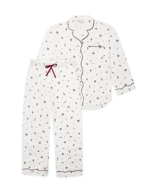 A two-piece pajama set featuring a long-sleeve button-front top and matching pants in white with a small dark floral print, accented by dark red piping and a red drawstring.
