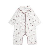 A baby long-sleeve footless romper in white cotton, decorated with a small red and green floral and dot pattern, featuring red piping along the collar, front placket, and leg openings.