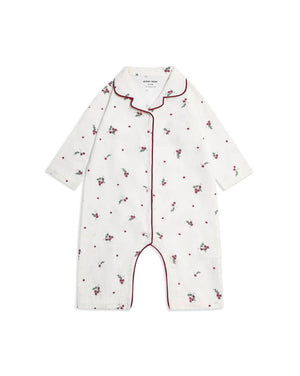 A baby long-sleeve footless romper in white cotton, decorated with a small red and green floral and dot pattern, featuring red piping along the collar, front placket, and leg openings.