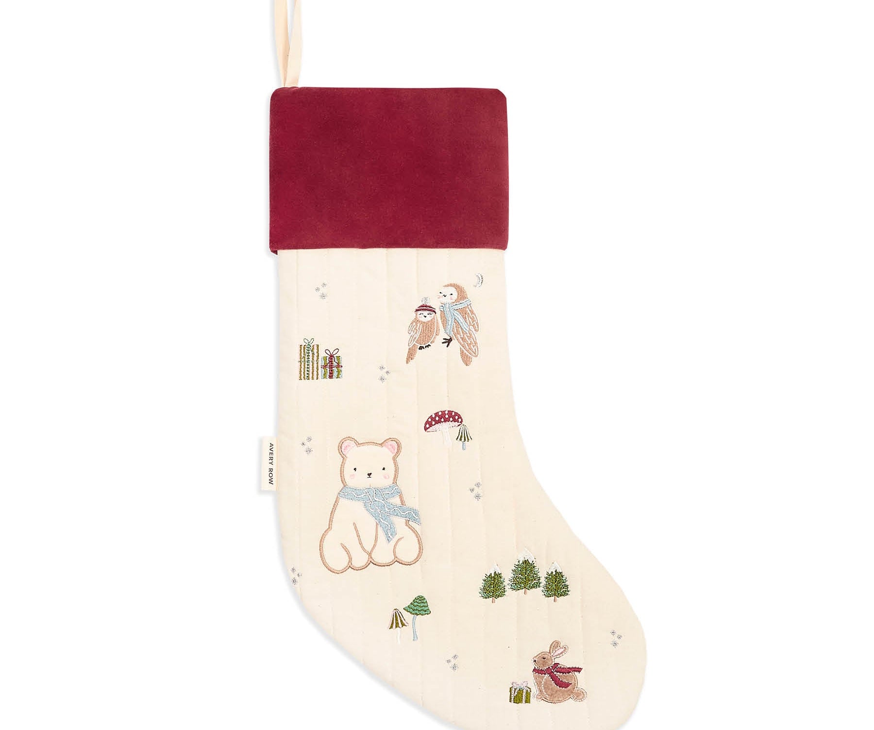 A Christmas stocking with a cream-colored body featuring embroidered teddy bears, birds, and trees, a dark red velvet cuff, and a hanging loop at the top.