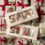 Two boxed sets of Avery Row Christmas tree decorations arranged on top of wrapped gift boxes with red ribbons and ornaments. The boxes contain small fabric holiday ornaments shaped like a bear, bird, tree, and other festive forms, visible through clear window packaging.