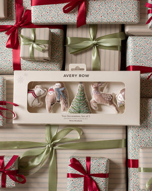 Avery Row Christmas tree decorations set of 5 in a cream-colored gift box, displayed on top of wrapped gift boxes with red ribbons and green satin bows.