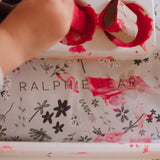 Hand interacting with a floral-patterned product box labeled 'Ralphie Bear'.