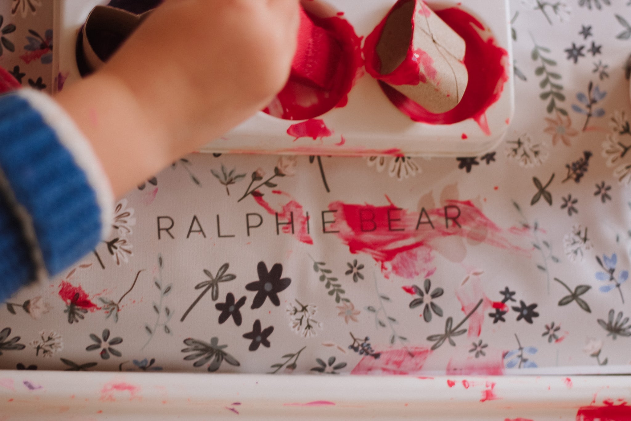 Hand interacting with a floral-patterned product box labeled 'Ralphie Bear'.