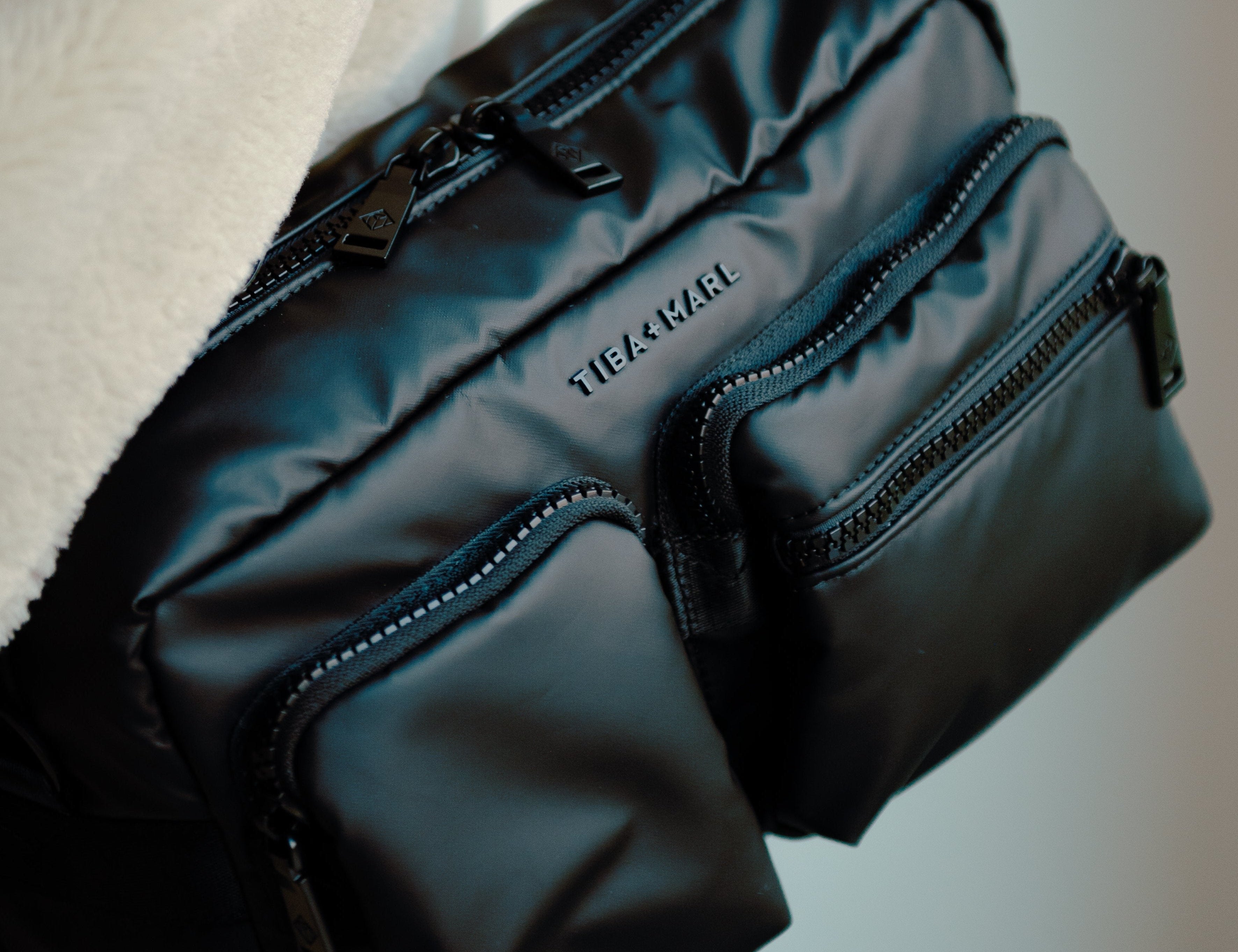 Black bag with visible brand name held by a person against a neutral background