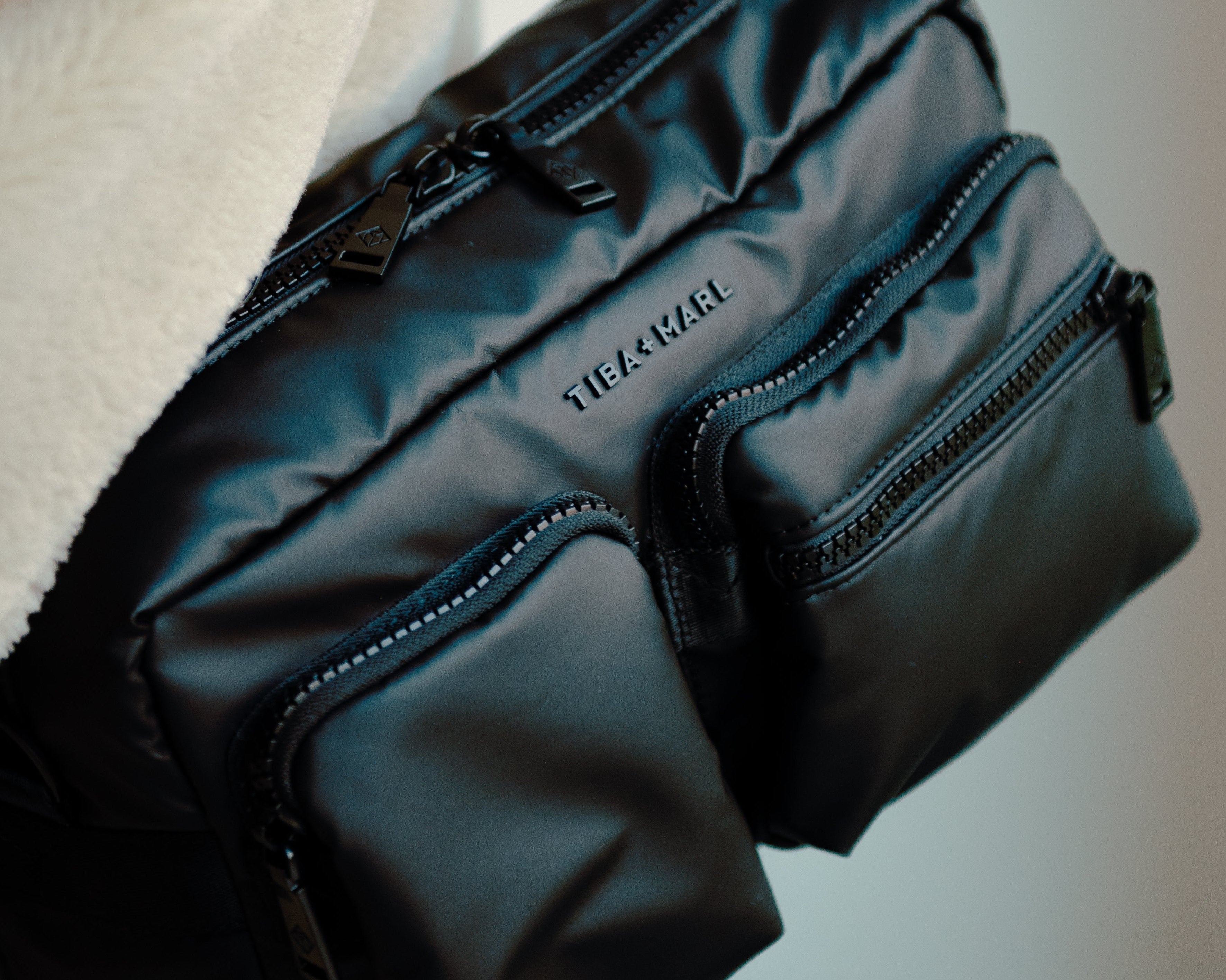 Black bag with visible brand name held by a person against a neutral background