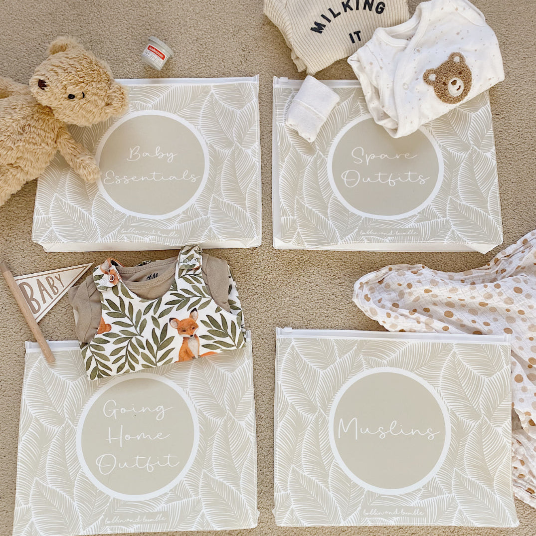 Hospital bag organiser pouches, beige leaf, four labelled pouches laid on carpet with baby clothes, muslin and a teddy