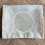 Hospital bag organiser pouches, beige leaf, flat pouch labelled Baby Essentials on a wooden floor