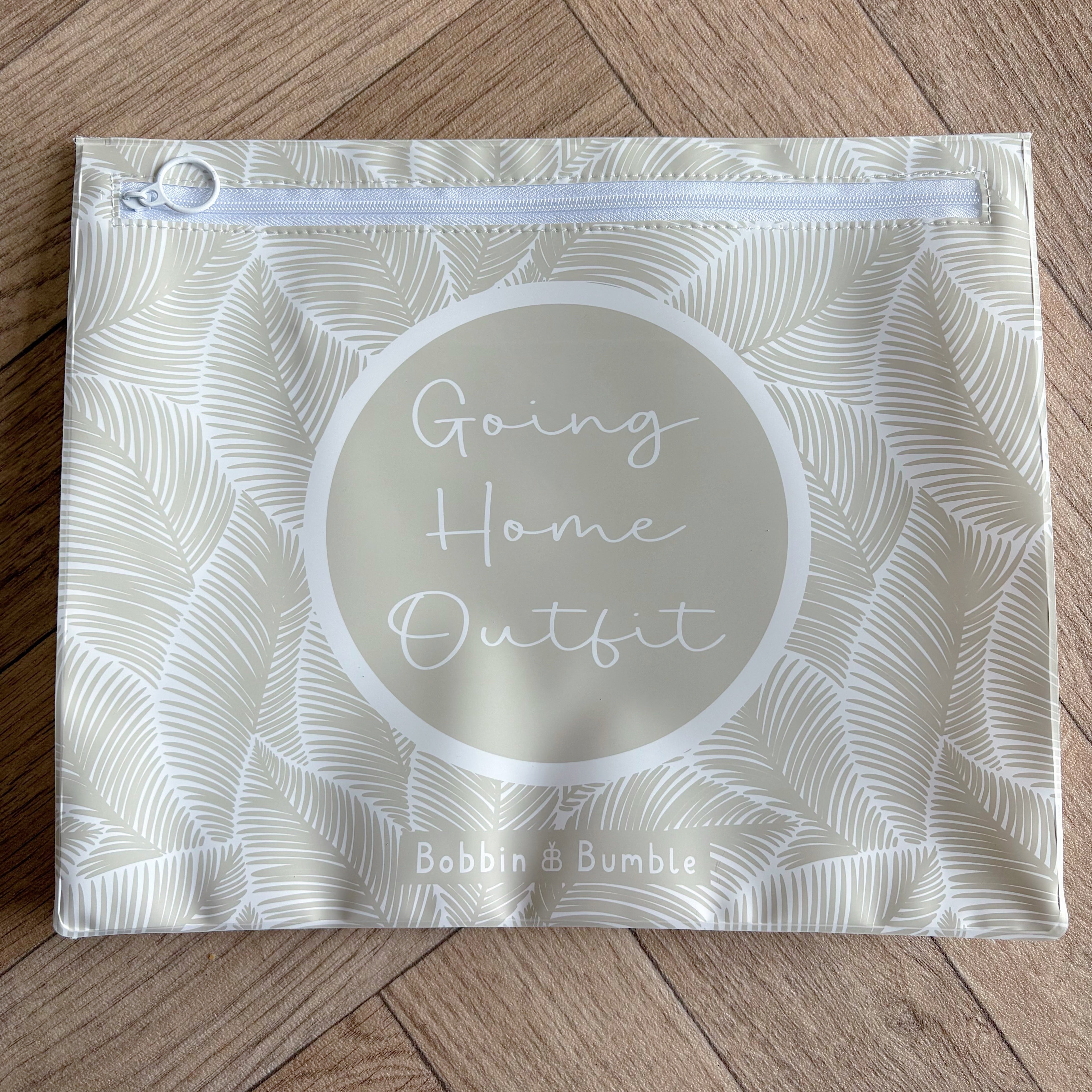 Hospital bag organiser pouches, beige leaf, flat pouch labelled Going Home Outfit on a wooden floor