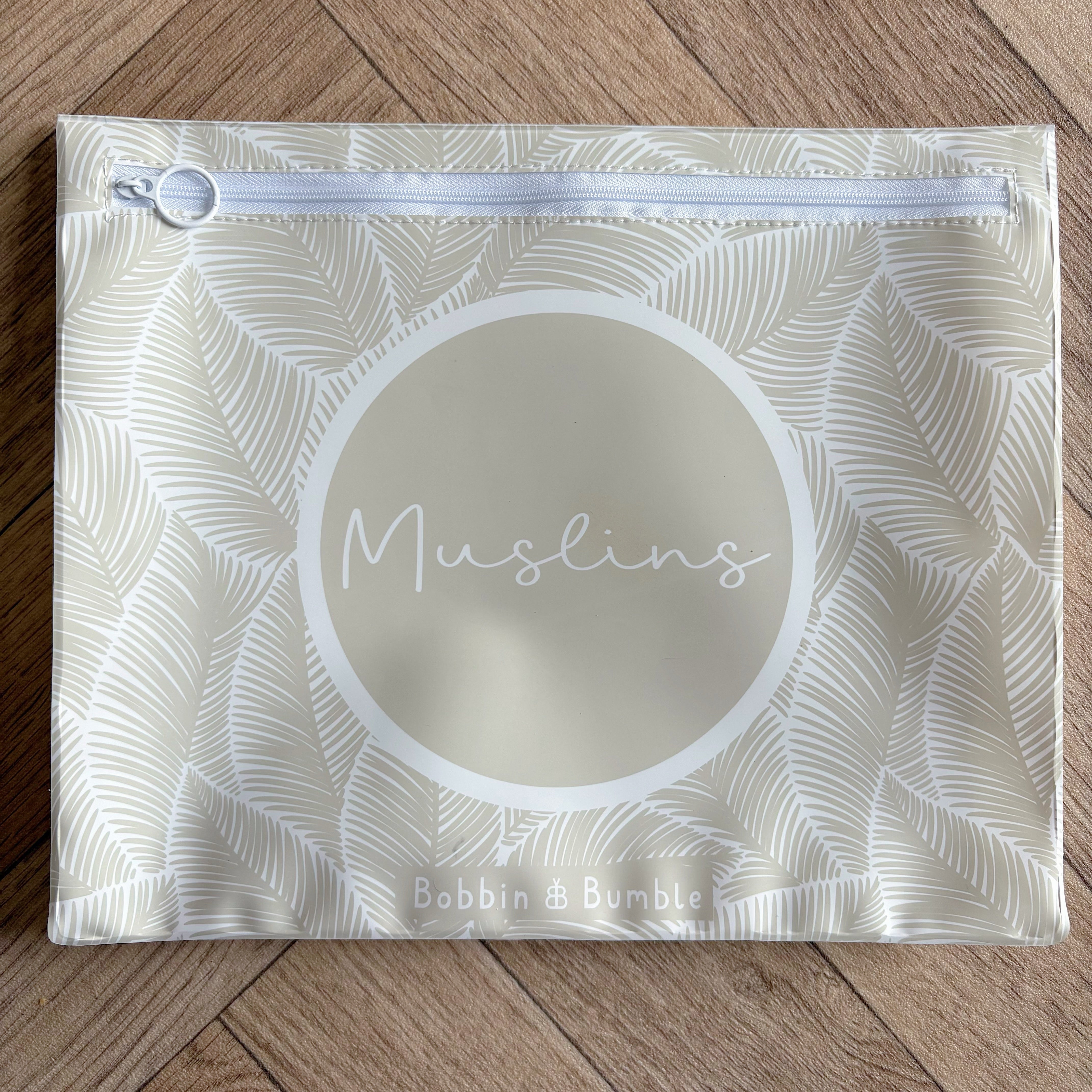 Hospital bag organiser pouches, beige leaf, flat pouch labelled Muslins on a wooden floor
