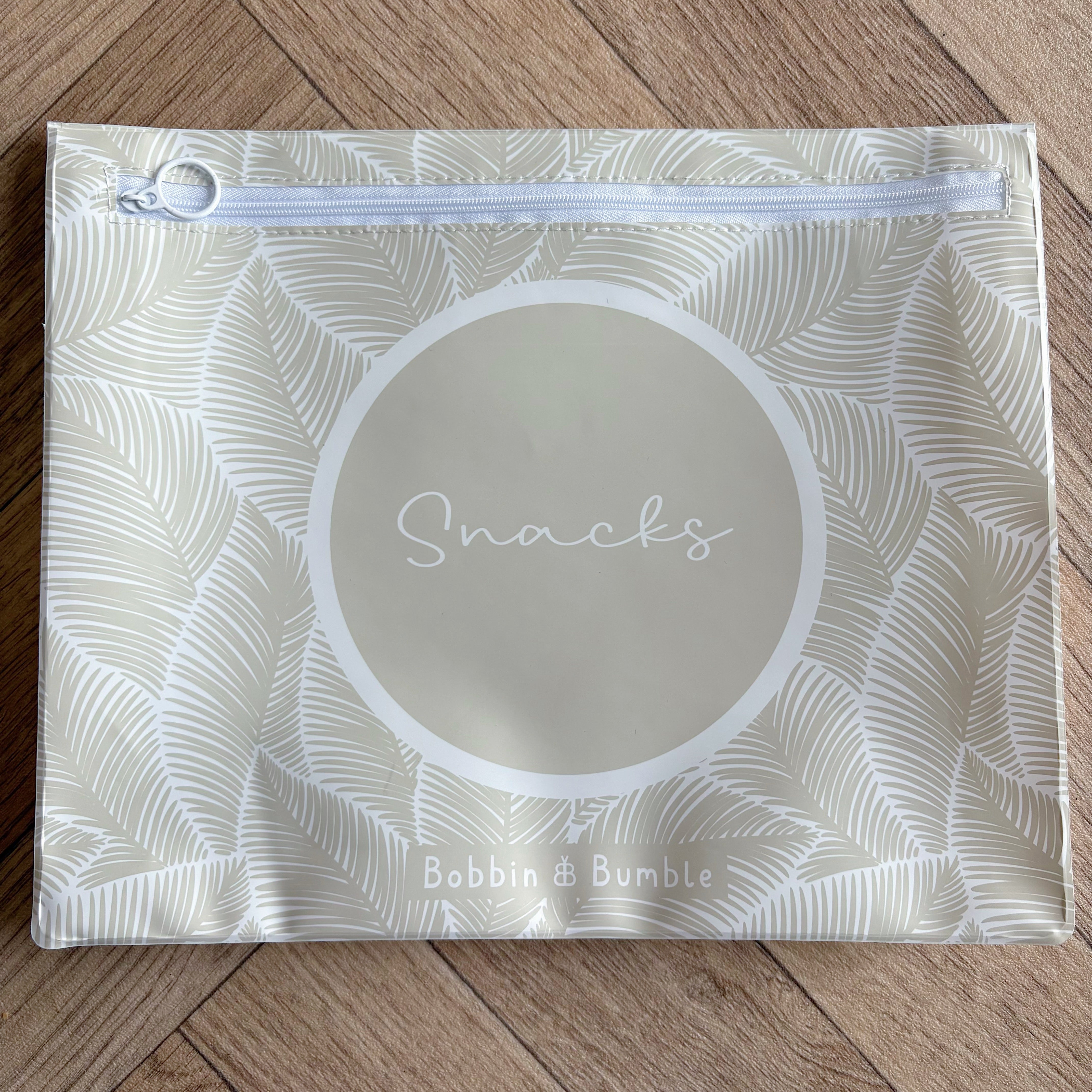 Hospital bag organiser pouches, beige leaf, flat pouch labelled Snacks on a wooden floor