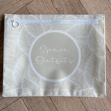 Hospital bag organiser pouches, beige leaf, flat pouch labelled Spare Outfits on a wooden floor