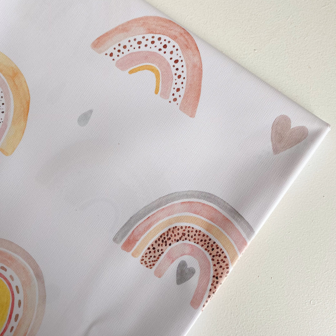 Splash Mat Beau Pink Rainbow Print, close-up of a folded corner showing pastel rainbows, hearts and raindrops on white