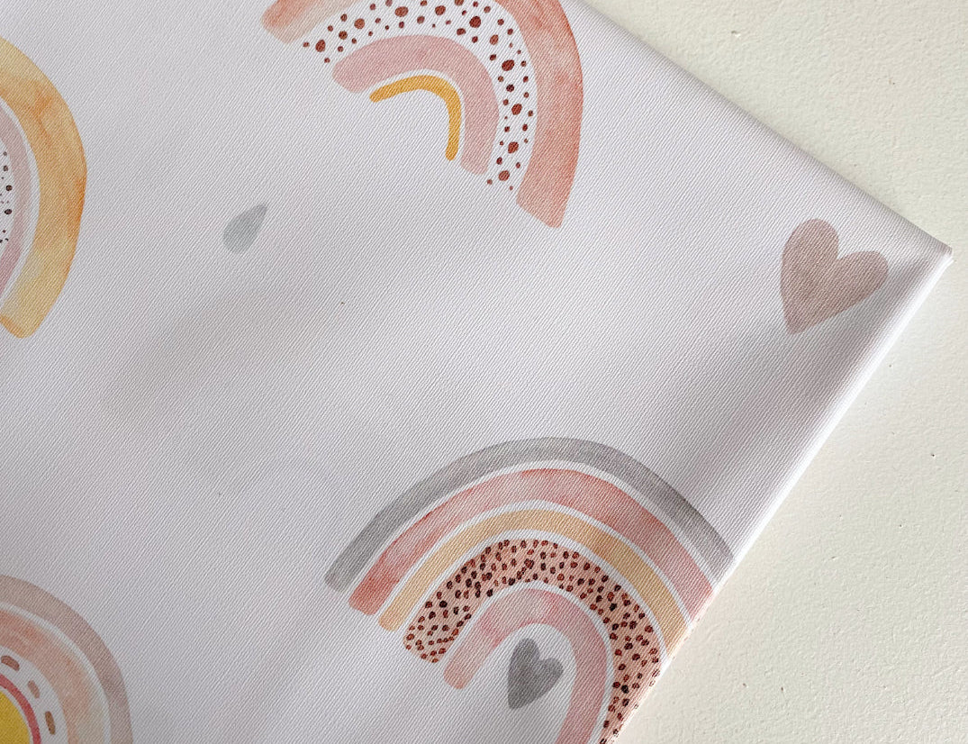 Splash Mat Beau Pink Rainbow Print, close-up of a folded corner showing pastel rainbows, hearts and raindrops on white