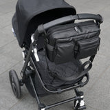 Black stroller with attached bag on a gray pavement