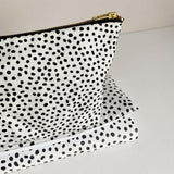 Nappy wallet in dalmatian print, close-up of the gold zip end and spotted fabric resting on the folded mat