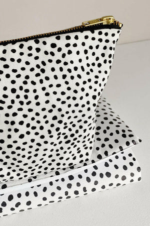 Nappy wallet in dalmatian print, close-up of the gold zip end and spotted fabric resting on the folded mat
