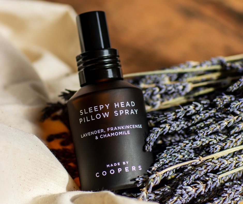Sleepy Head Pillow Spray bottle tilted on a bunch of dried lavender and cream cloth