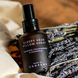 Sleepy Head Pillow Spray bottle tilted on a bunch of dried lavender and cream cloth