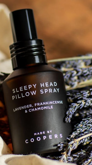 Sleepy Head Pillow Spray bottle tilted on a bunch of dried lavender and cream cloth
