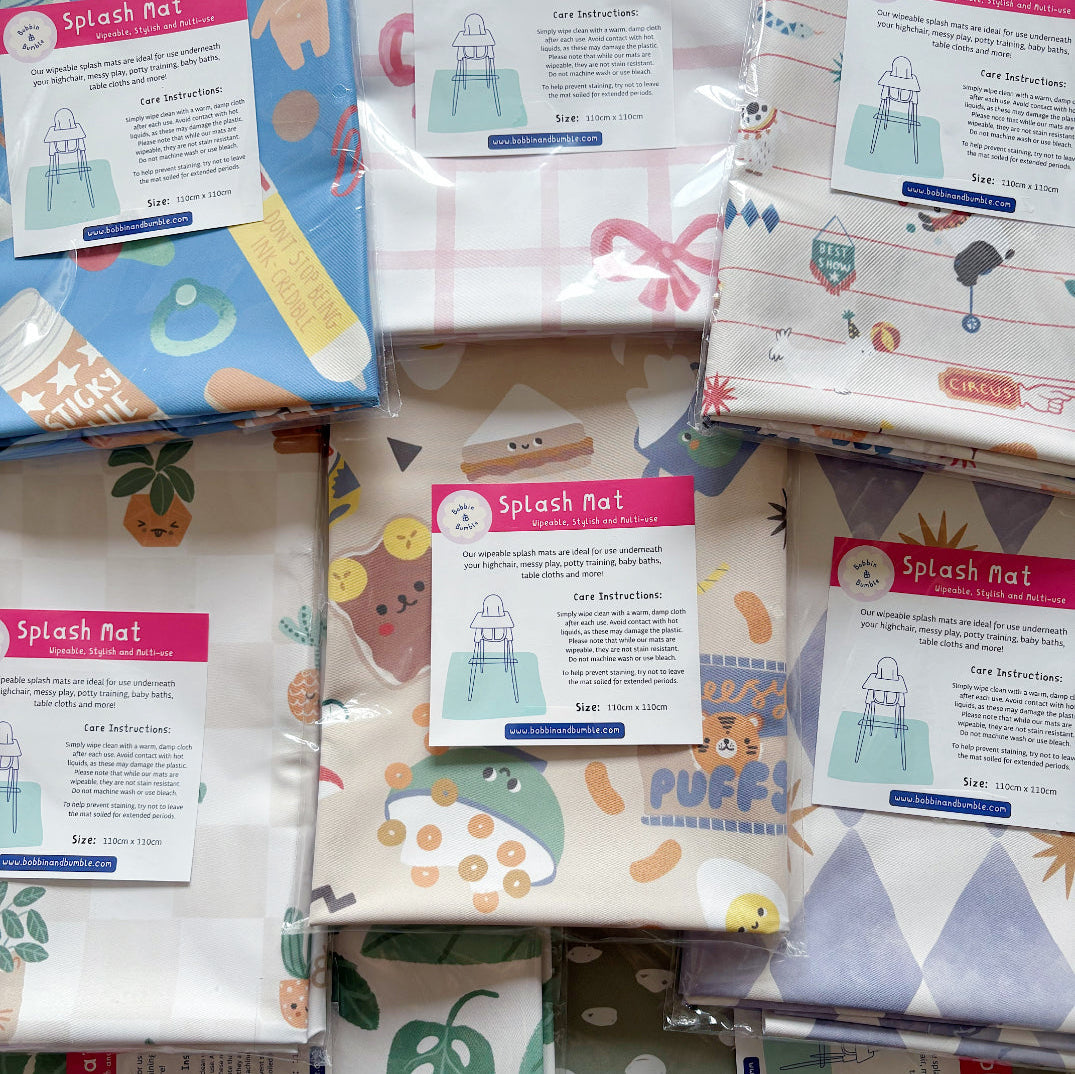 Stack of packaged splash mats in different prints, including Pot Plants, pink bow, circus animals and cereal snacks