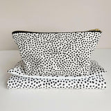 Nappy wallet in dalmatian print, standing upright on top of a matching spotted folded changing mat