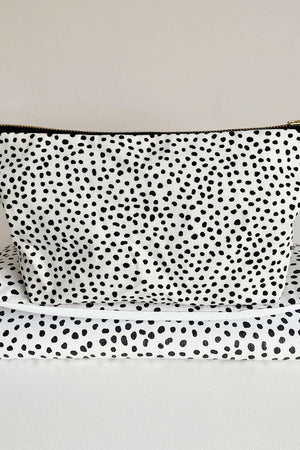 Nappy wallet in dalmatian print, standing upright on top of a matching spotted folded changing mat