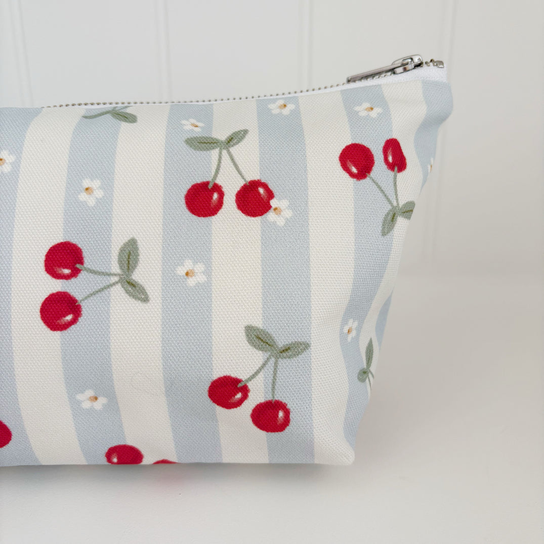Nappy Wallet Cherry Stripe, close-up of the cherry and daisy print on the left side with the zip pull at the top right