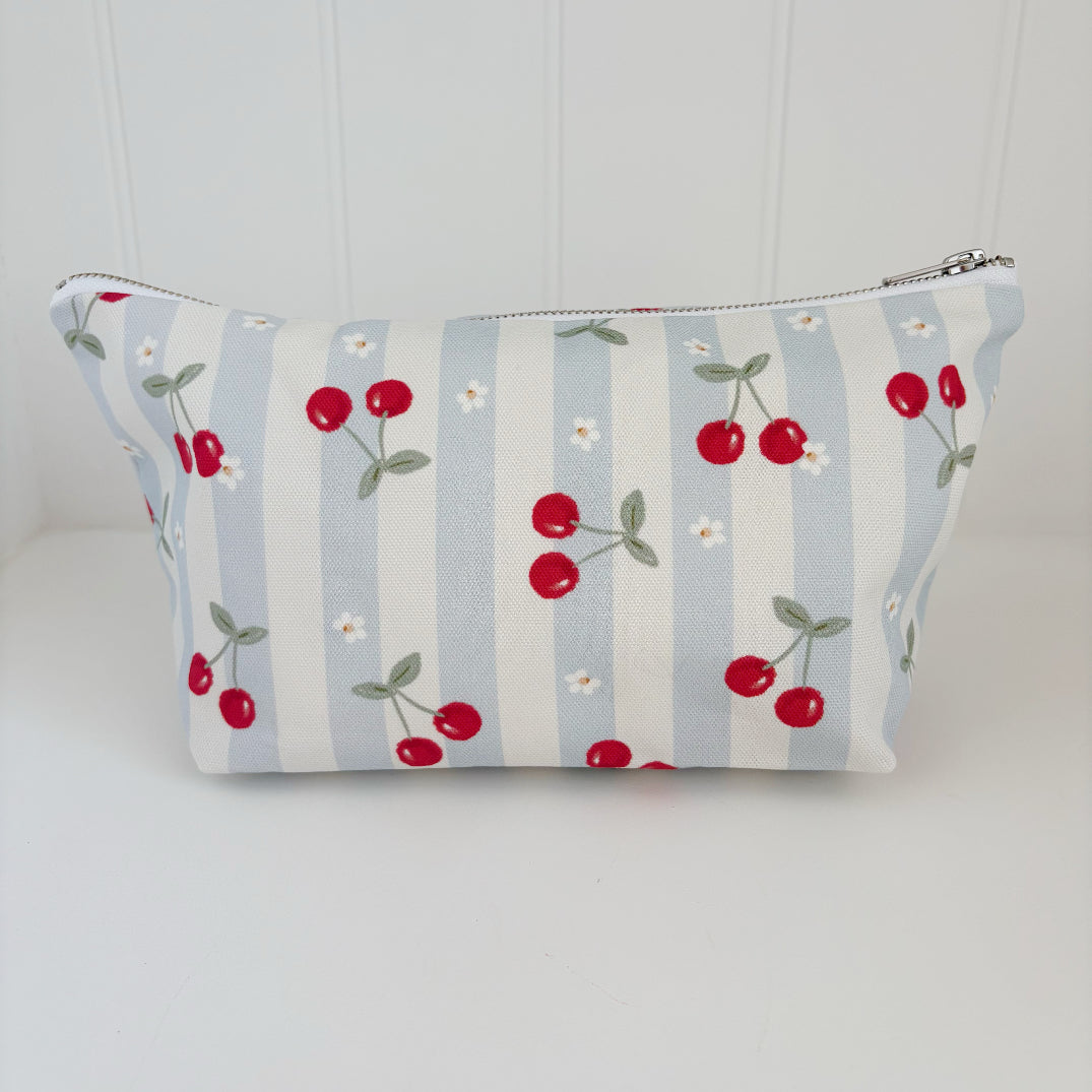 Nappy Wallet Cherry Stripe, front view of blue and cream striped zipped pouch with red cherries and small white flowers
