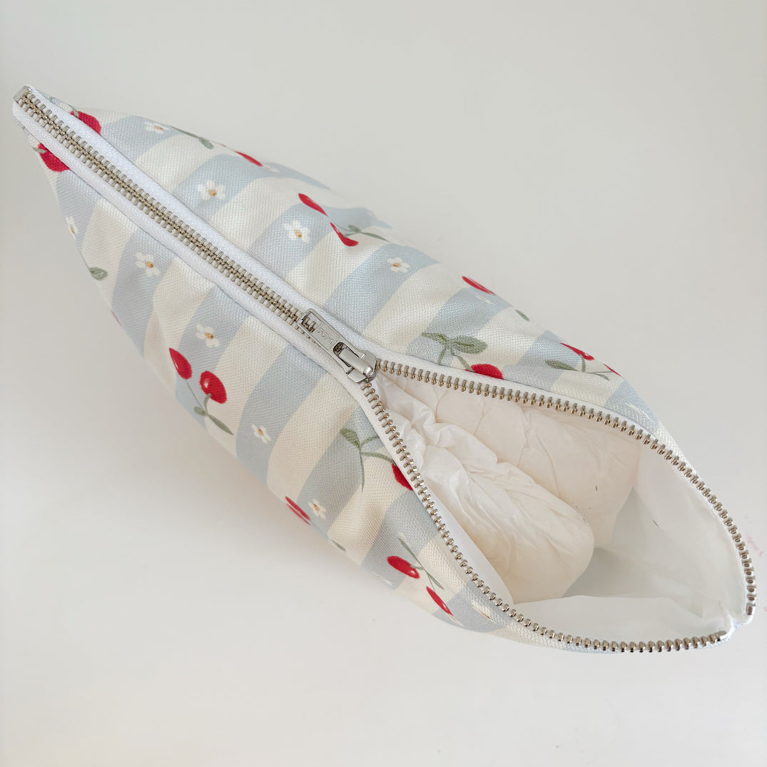 Nappy Wallet Cherry Stripe, partly unzipped with a nappy visible inside the white lining