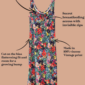 A sleeveless vintage floral print maternity dress with text callouts explaining its features, including adjustable neckline, secret breastfeeding access with invisible zips, and a 100% viscose vintage print, set against a solid tan background.
