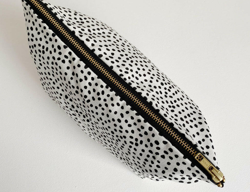 Nappy wallet in dalmatian print, seen from above with the gold zip closed along the top of the pouch