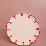 Rosy Red Scalloped Lunch Plate, front view of one cream plate with a red looped scalloped edge on a pink backdrop