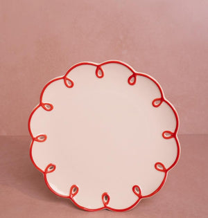 Rosy Red Scalloped Lunch Plate, front view of one cream plate with a red looped scalloped edge on a pink backdrop