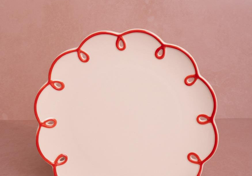 Rosy Red Scalloped Lunch Plate, front view of one cream plate with a red looped scalloped edge on a pink backdrop