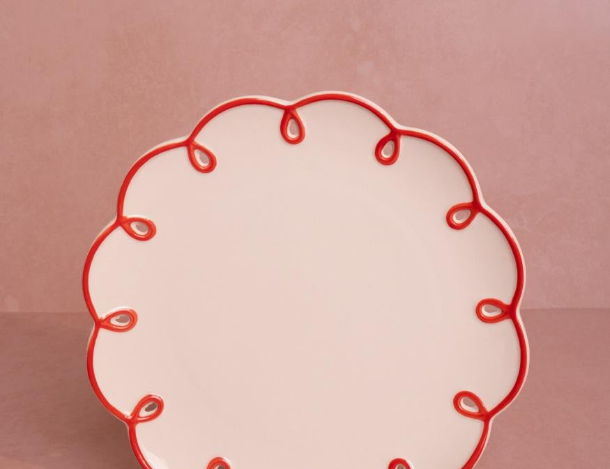 Rosy Red Scalloped Lunch Plate, front view of one cream plate with a red looped scalloped edge on a pink backdrop