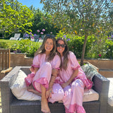 Two women in pink robes sitting on a garden sofa with a garden background
