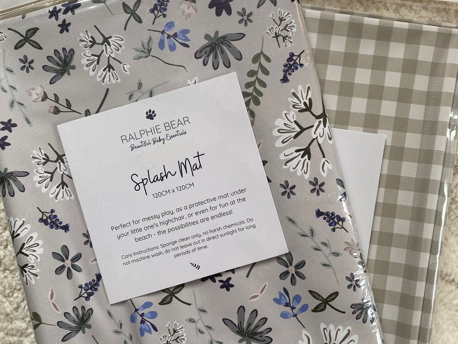 Two patterned splash mats with a label on a textured surface