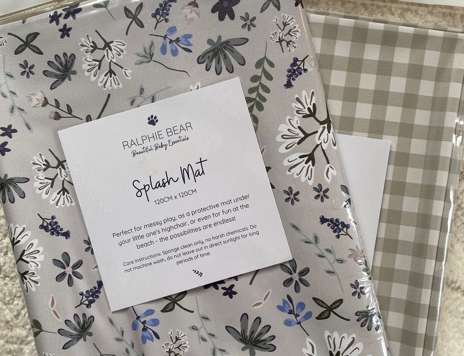 Two patterned splash mats with a label on a textured surface