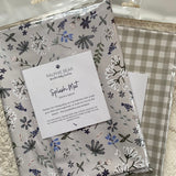 Two patterned splash mats with a label on a textured surface