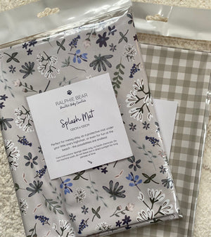 Two patterned splash mats with a label on a textured surface