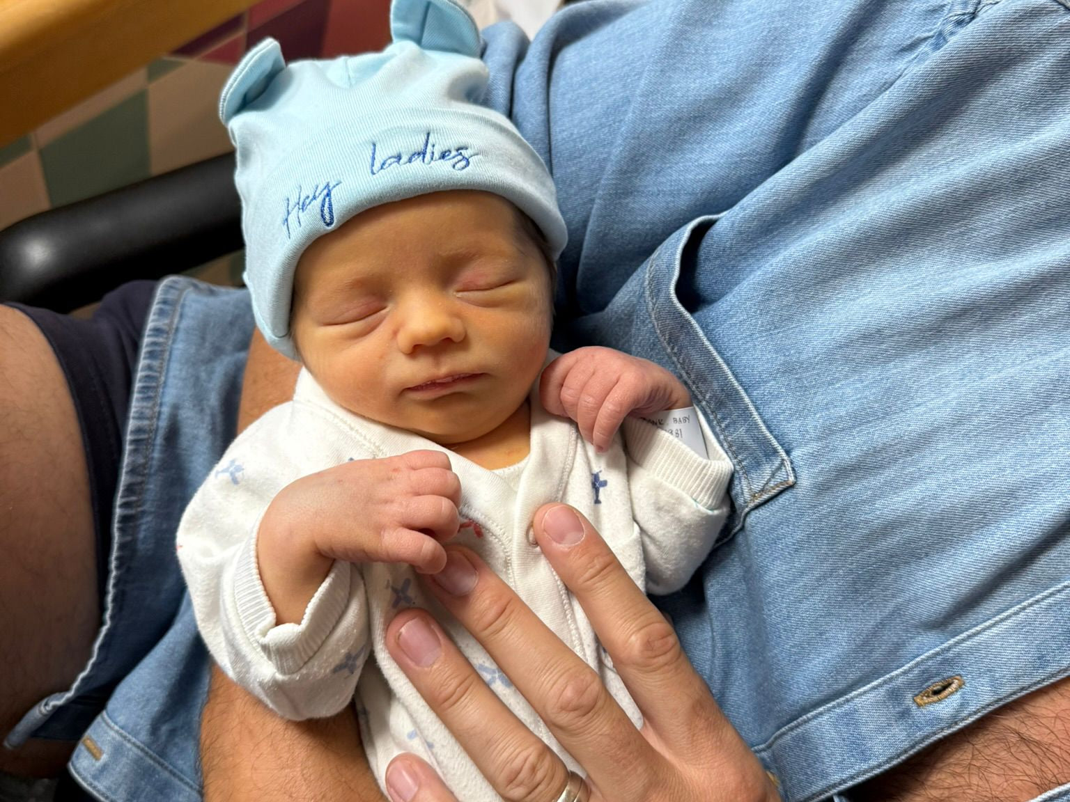 Newborn baby being held by an adult in a casual setting