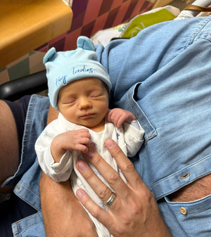 Newborn baby being held by an adult in a casual setting