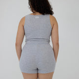 A woman shown from the back wearing a heather gray sleeveless tank top and matching high-waisted shorts against a plain light gray studio background.