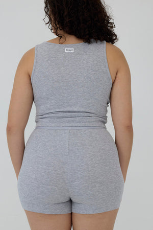 A woman shown from the back wearing a heather gray sleeveless tank top and matching high-waisted shorts against a plain light gray studio background.