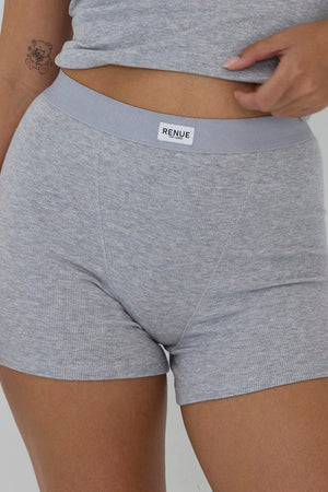 A close-up of a model wearing heather gray ribbed boxer briefs with a light gray elastic waistband and a visible RENSE brand label.