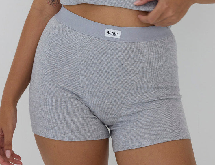 A close-up of a model wearing heather gray ribbed boxer briefs with a light gray elastic waistband and a visible RENSE brand label.
