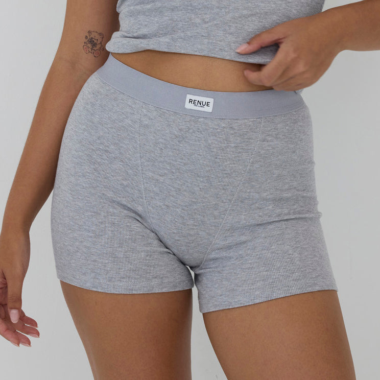 A close-up of a model wearing heather gray ribbed boxer briefs with a light gray elastic waistband and a visible RENSE brand label.