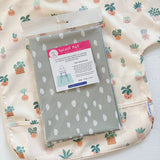 Splash Mat Sage Spots, in its packaging on a cream bib with a potted plant print